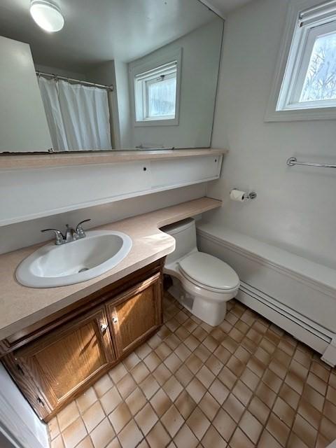 bathroom with a baseboard heating unit, curtained shower, toilet, and vanity