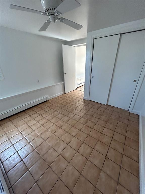 unfurnished bedroom with a closet, baseboard heating, and a ceiling fan