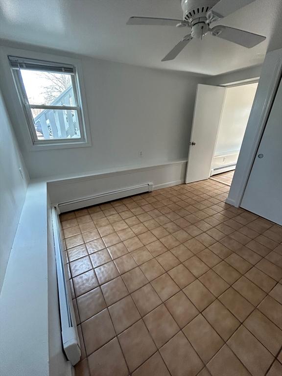 empty room featuring a ceiling fan and baseboard heating