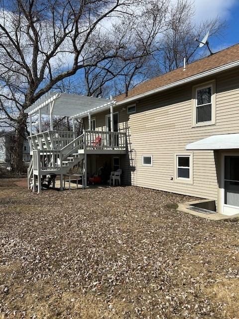 rear view of property featuring a deck, stairway, and a pergola