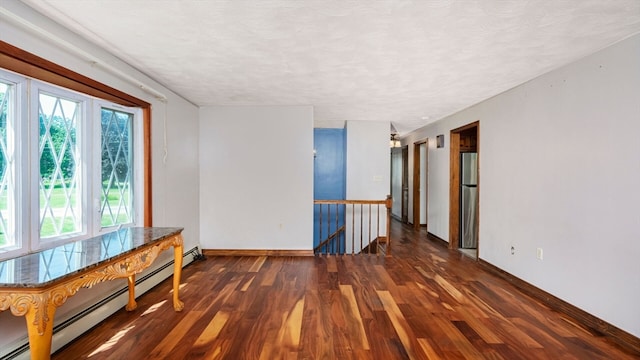 spare room with a textured ceiling, dark hardwood / wood-style flooring, and a baseboard heating unit