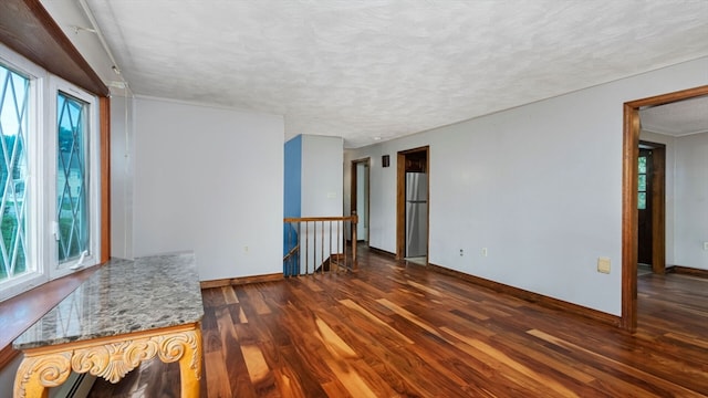 empty room with dark wood-type flooring and a textured ceiling