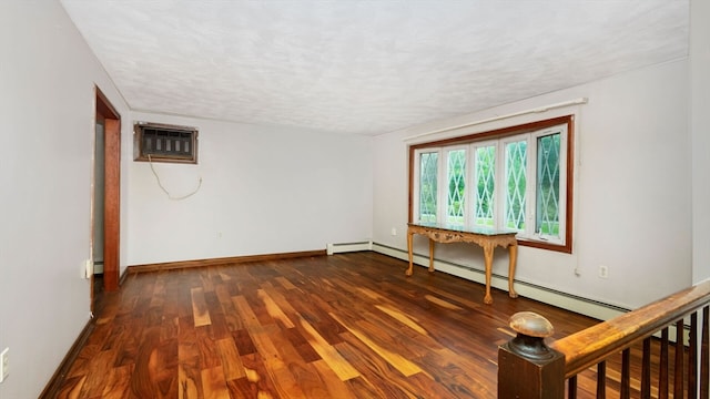 unfurnished room featuring a textured ceiling, a baseboard heating unit, a wall mounted AC, and dark hardwood / wood-style flooring