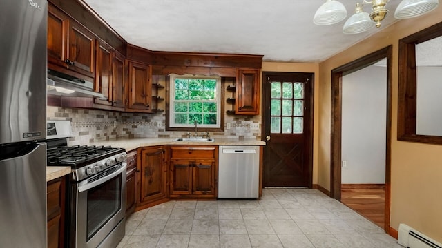 kitchen with sink, backsplash, a baseboard heating unit, appliances with stainless steel finishes, and range hood