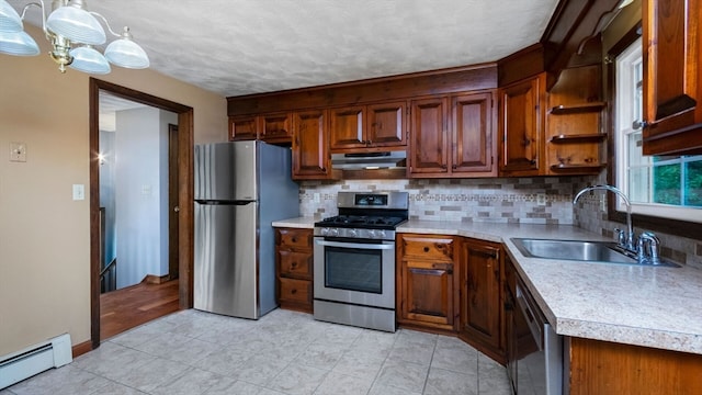 kitchen featuring sink, a baseboard heating unit, appliances with stainless steel finishes, decorative light fixtures, and backsplash