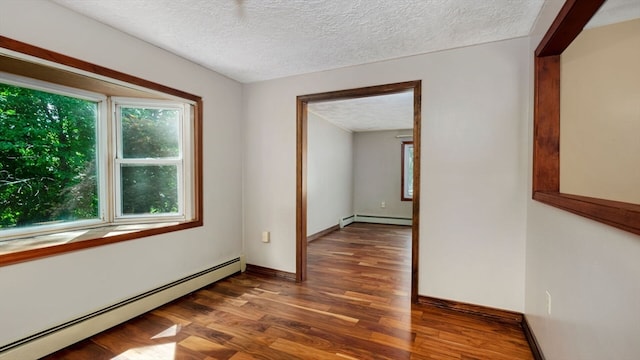 spare room with a textured ceiling, baseboard heating, and dark wood-type flooring