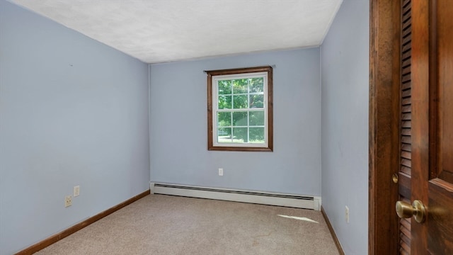 carpeted empty room featuring baseboard heating