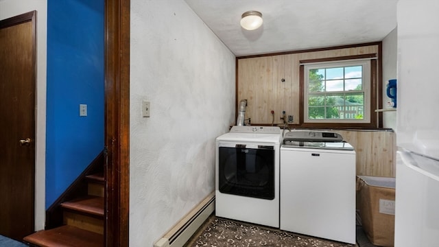 washroom with wood walls, washer and clothes dryer, and a baseboard radiator