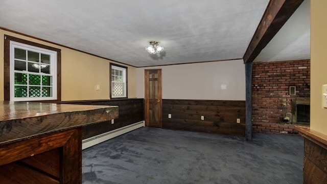 interior space featuring wood walls, beam ceiling, a textured ceiling, a baseboard heating unit, and a fireplace