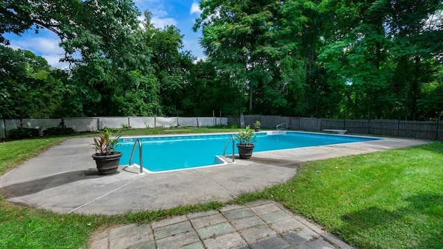 view of pool featuring a patio, a lawn, and a diving board