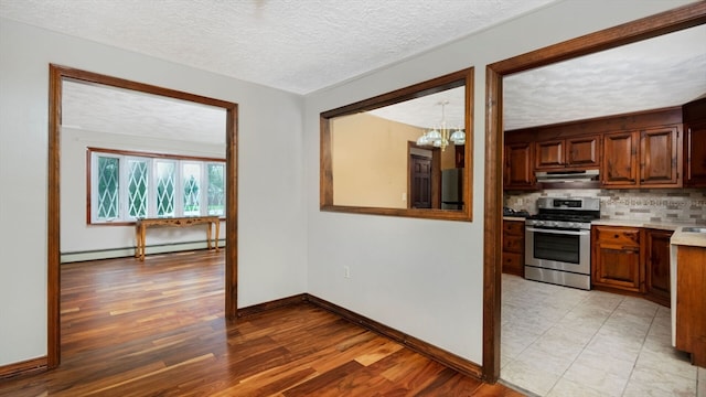 kitchen with baseboard heating, appliances with stainless steel finishes, light hardwood / wood-style flooring, and a textured ceiling