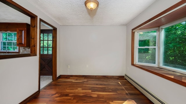 unfurnished dining area featuring a textured ceiling, sink, a baseboard heating unit, and dark hardwood / wood-style flooring