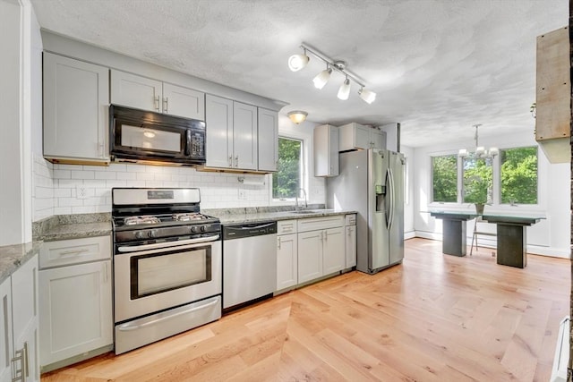 825 S St, Tewksbury, MA 01876 - kitchen with appliances with stainless steel finishes, backsplash, a chandelier, light stone countertops, and a sink