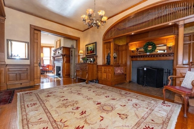 sitting room featuring an inviting chandelier, a fireplace with flush hearth, ornamental molding, and wood finished floors