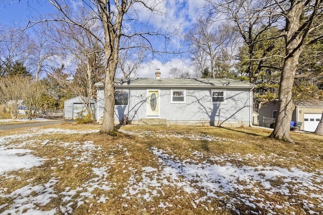 snow covered back of property featuring a garage