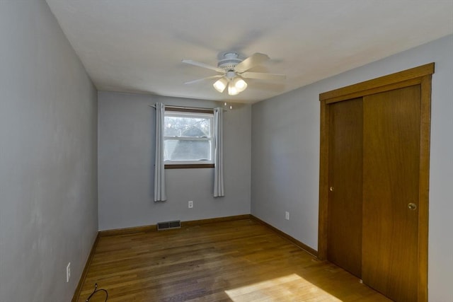 unfurnished bedroom with wood-type flooring, a closet, and ceiling fan