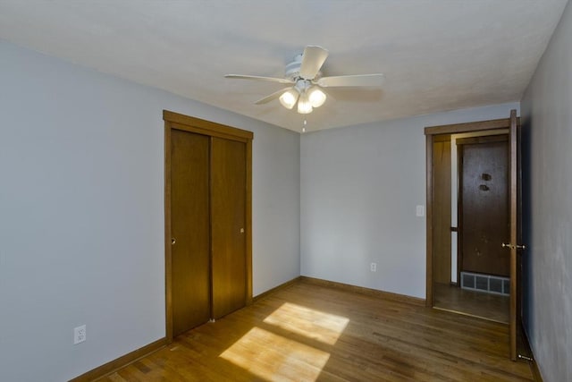 unfurnished bedroom featuring hardwood / wood-style floors, ceiling fan, and a closet