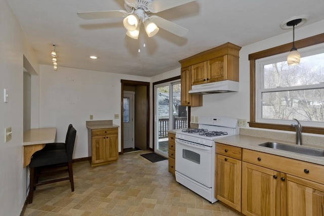 kitchen with white gas range, hanging light fixtures, sink, and ceiling fan