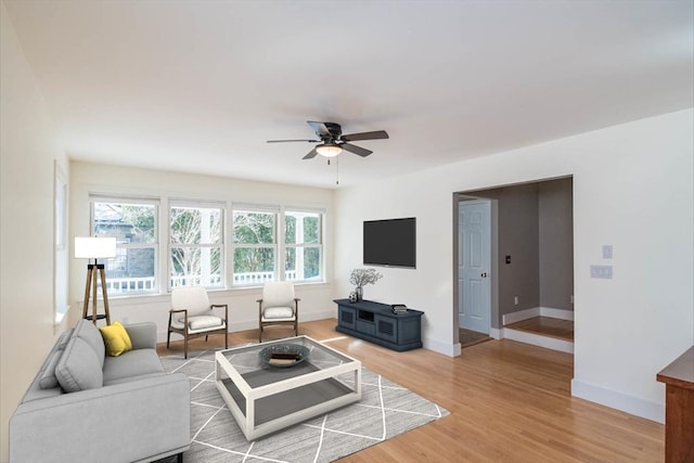 living area featuring light wood-type flooring, ceiling fan, and baseboards