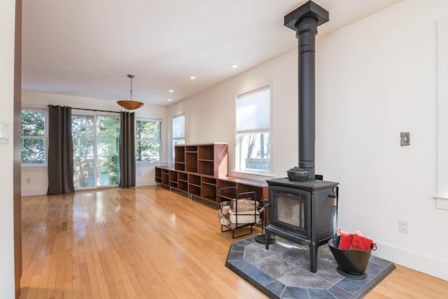 living area with a wood stove, baseboards, wood finished floors, and recessed lighting