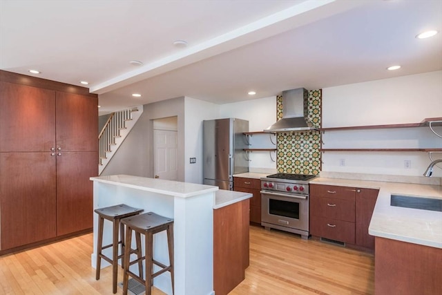 kitchen with open shelves, a sink, wall chimney range hood, light wood-type flooring, and luxury stove