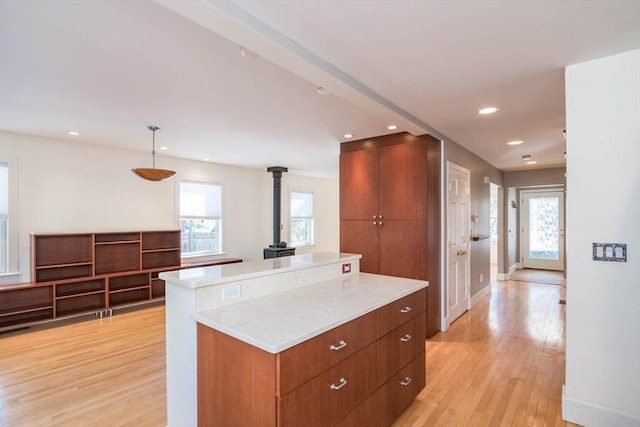 kitchen featuring light wood finished floors, recessed lighting, light countertops, a wood stove, and modern cabinets