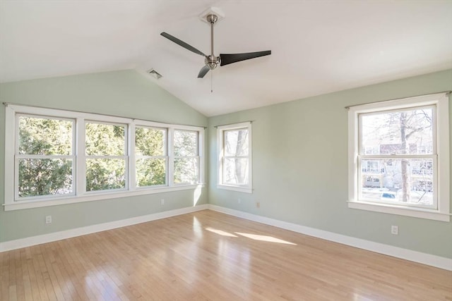 spare room with lofted ceiling, visible vents, light wood-style flooring, and baseboards