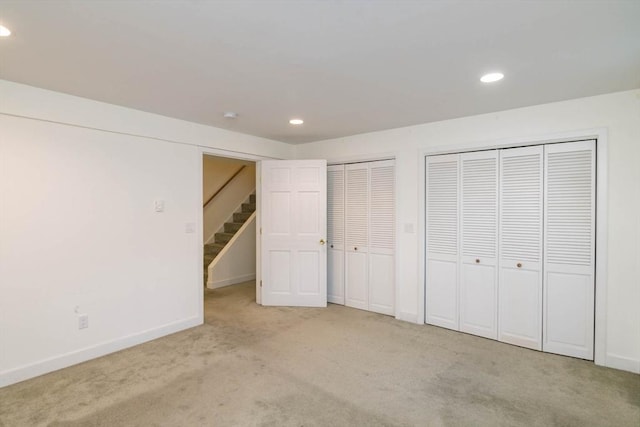 unfurnished bedroom featuring recessed lighting, baseboards, multiple closets, and light colored carpet