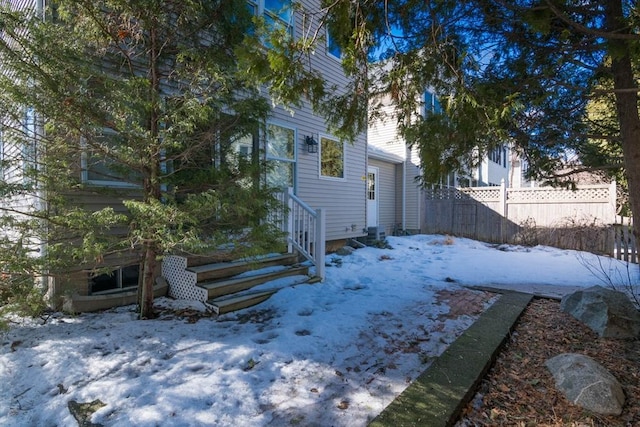 snowy yard featuring entry steps and fence