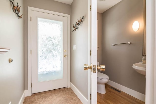 half bath featuring toilet, baseboards, and visible vents