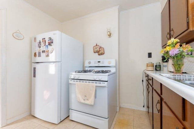 kitchen with light tile patterned floors, white appliances, crown molding, and light countertops