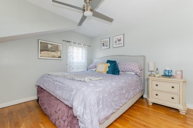 bedroom featuring vaulted ceiling, baseboards, light wood finished floors, and ceiling fan