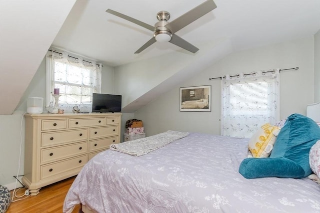 bedroom featuring ceiling fan, light wood-style flooring, and vaulted ceiling