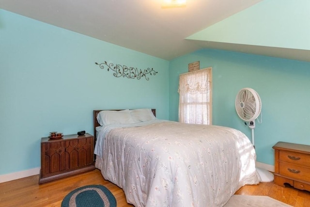 bedroom with lofted ceiling, baseboards, and light wood finished floors