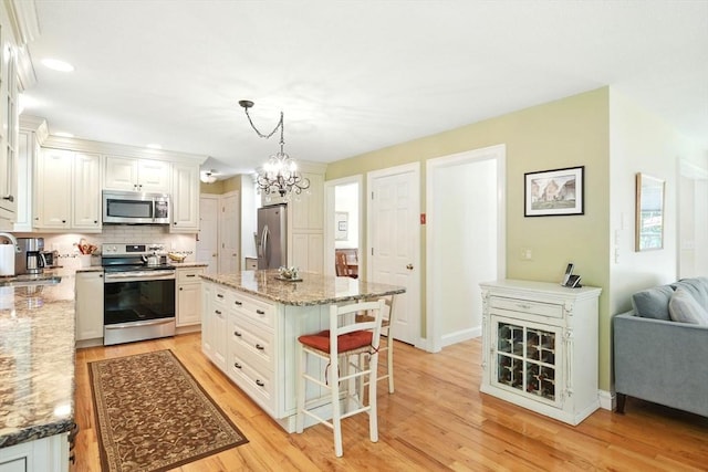 34 Hawks Cir, Westfield, MA 01085 - kitchen featuring appliances with stainless steel finishes, light wood-style floors, a kitchen breakfast bar, a chandelier, and decorative backsplash
