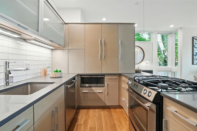 89 Kirkland St Unit 89, Cambridge, MA 02138 - kitchen with stainless steel appliances, decorative backsplash, dark stone countertops, light wood-style flooring, and modern cabinets