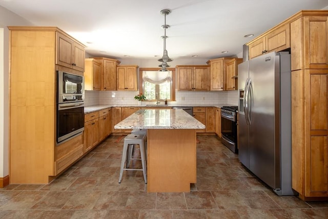kitchen with light stone countertops, appliances with stainless steel finishes, stone finish floor, backsplash, and a kitchen island
