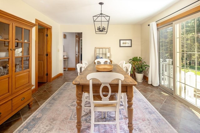 dining room with dark tile patterned floors, baseboards, and a chandelier