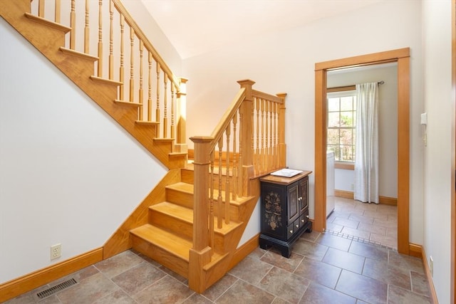 staircase with stone tile floors, baseboards, and visible vents