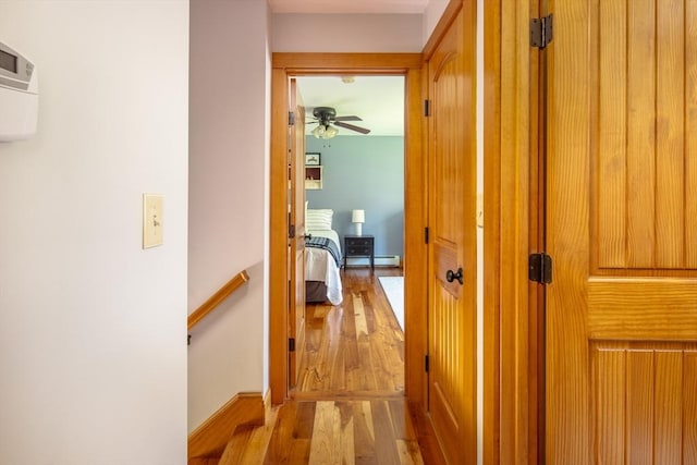 hall with an upstairs landing, light wood finished floors, and a baseboard radiator