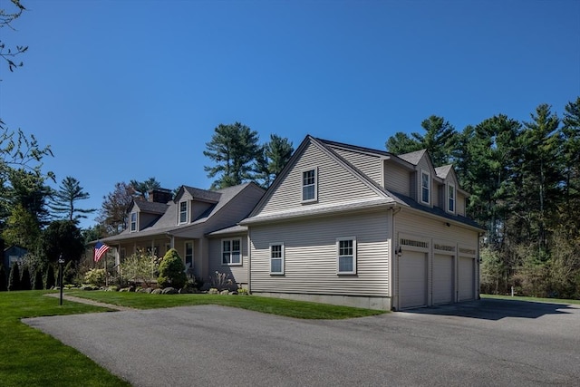 view of front of property featuring a garage, a front yard, and aphalt driveway