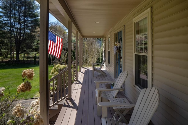 wooden terrace with a lawn and a porch