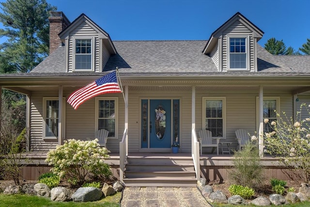 view of front of property with roof with shingles, covered porch, and a chimney