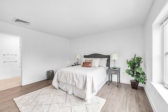 bedroom with wood-type flooring and connected bathroom