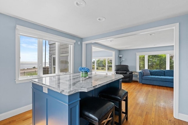 70 Williams St, Quincy, MA 02171 - kitchen with light stone countertops, light wood-style flooring, a kitchen bar, a kitchen island, and open floor plan