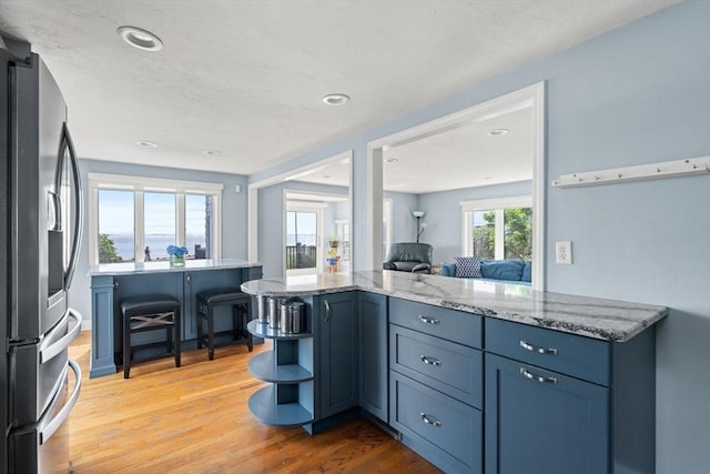 70 Williams St, Quincy, MA 02171 - kitchen featuring stainless steel fridge, light stone counters, open shelves, light wood-type flooring, and recessed lighting