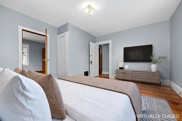 bedroom with a closet, baseboards, and wood finished floors