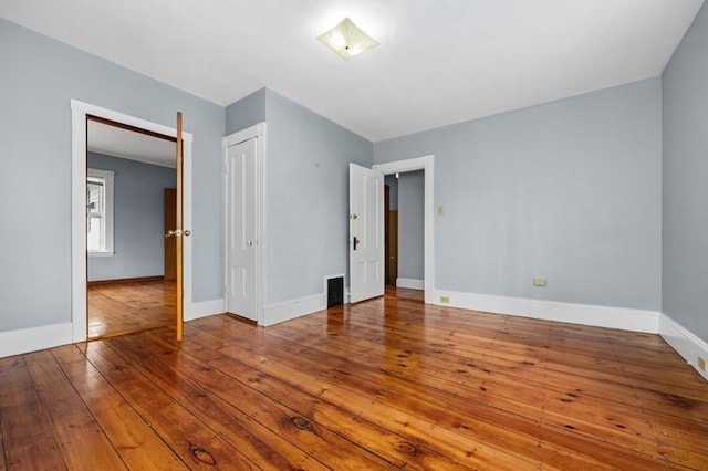 unfurnished bedroom featuring a closet, hardwood / wood-style flooring, and baseboards