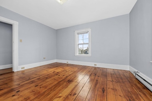 spare room with baseboards, baseboard heating, and hardwood / wood-style floors