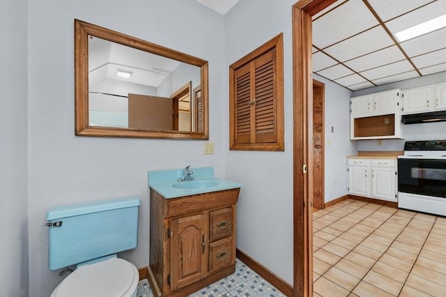 bathroom with a paneled ceiling, vanity, toilet, and baseboards